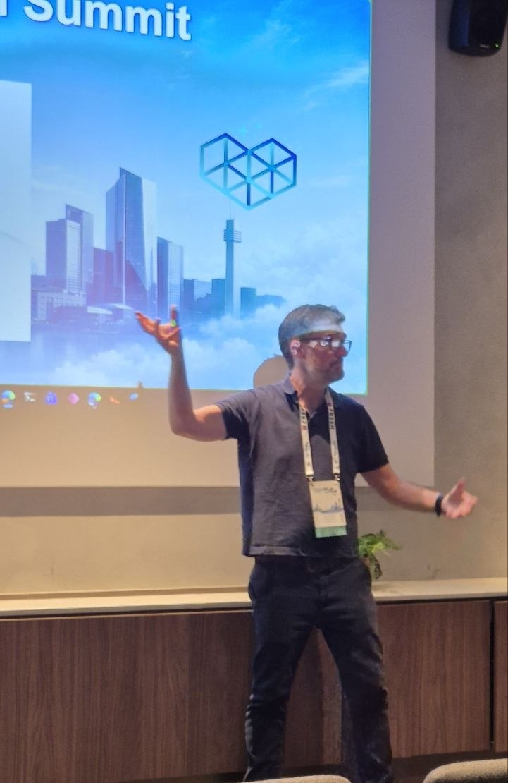 Ferran Chopo speaking with both hands raised in front of the HELish Summit skyline slide