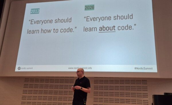Jukka Niiranen on stage in the Duplo hall at Nordic Summit 2026 under a slide comparing 2012: everyone should learn how to code, with 2026: everyone should learn about code